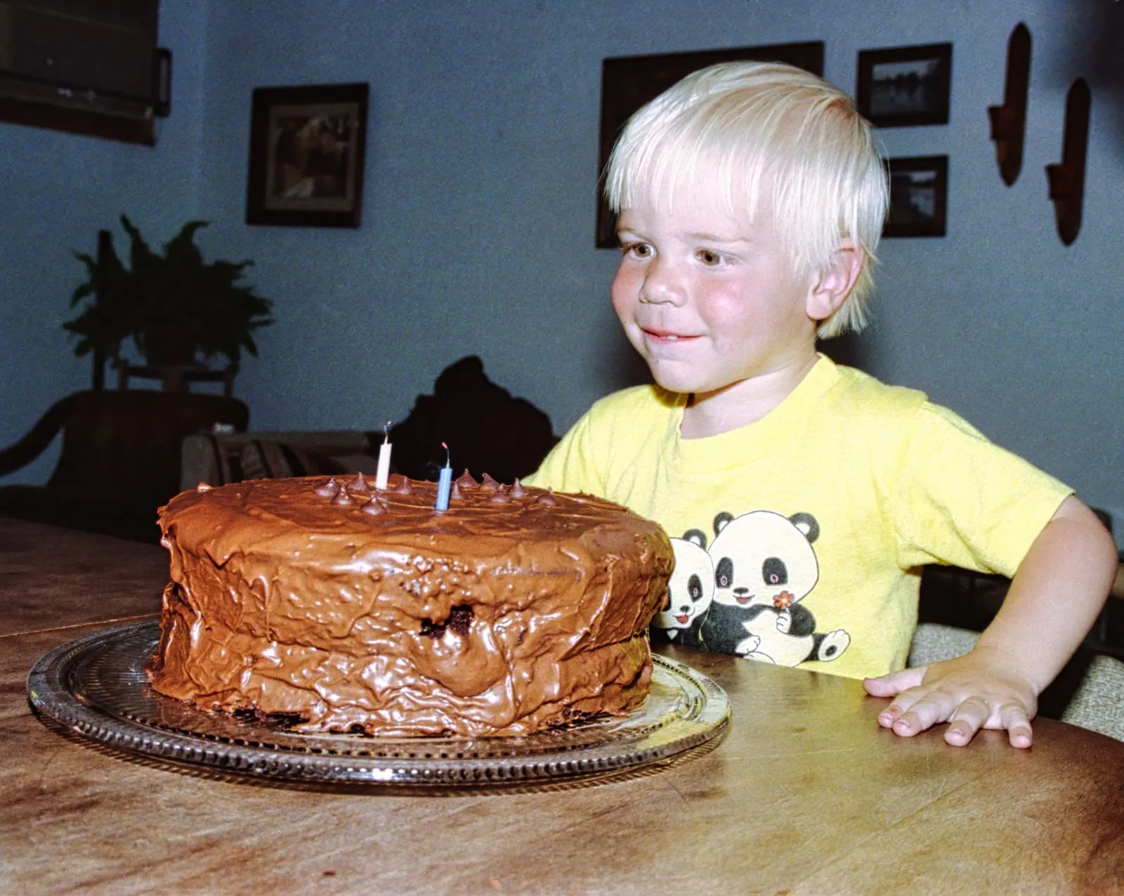 A young boy eagerly anticipates his chocolate birthday cake with lit candles in a cozy indoor setting. Celebrities born on July 4: a US Independence Day birthday list