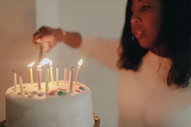 A woman lights candles on a birthday cake indoors, creating a festive and warm atmosphere. Good choices about historical figures with July birthdays start with the fundamentals