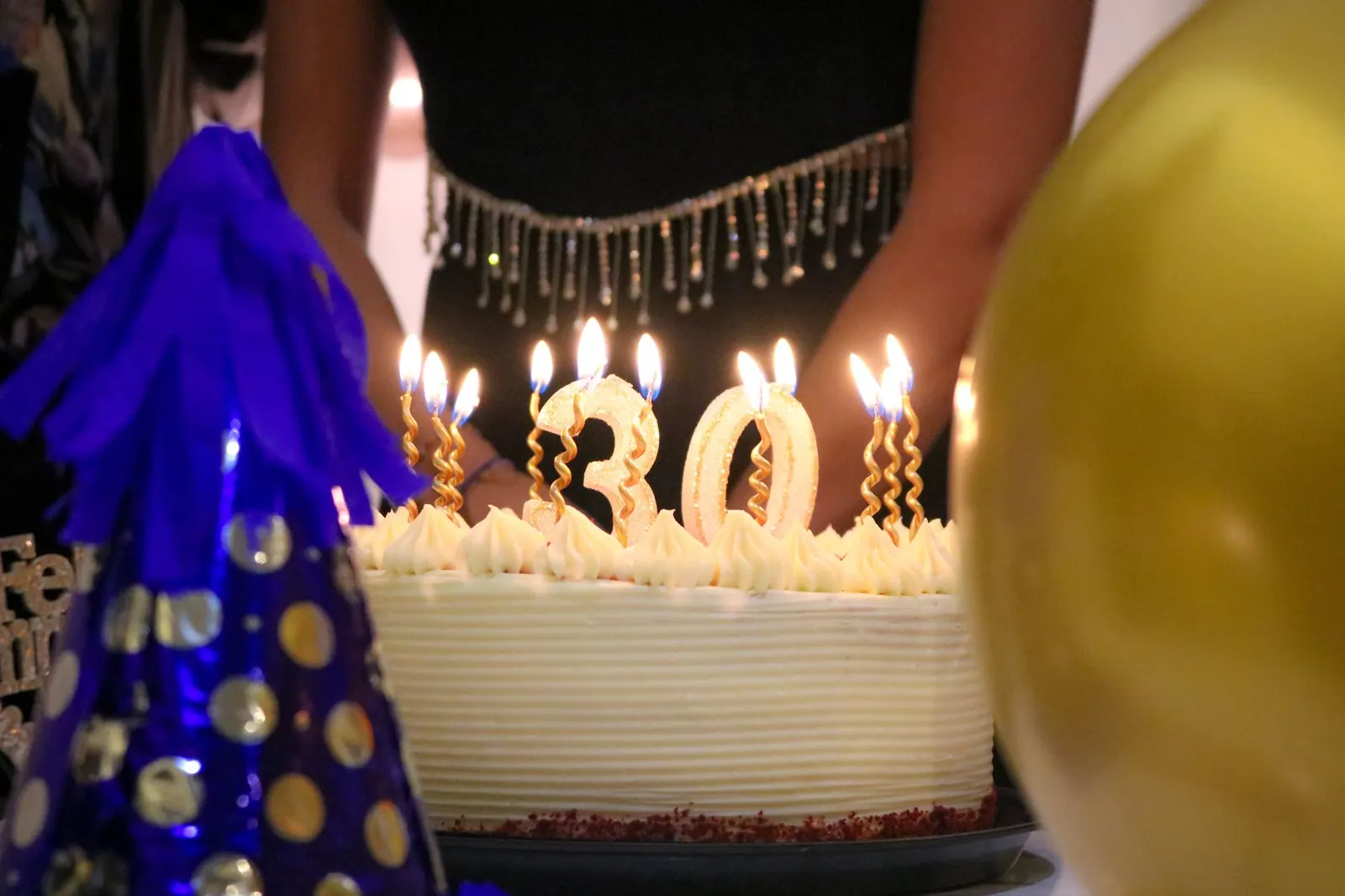 Close-up of a birthday cake with '30' candles at a festive celebration. June birthdays by day: notable people organized by date